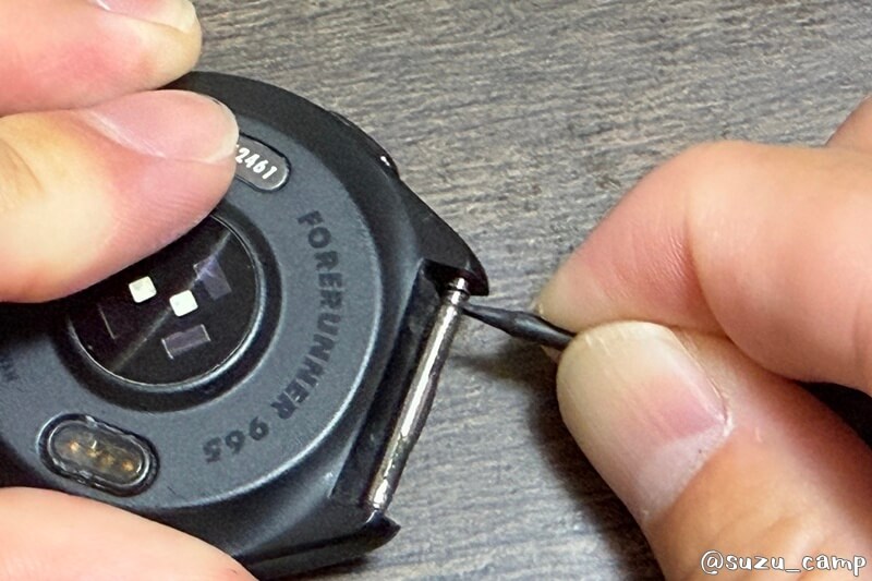 工具でバネ棒の端を内側に押し込み、時計本体の穴から外す操作